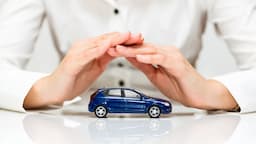 Hands covering a small blue car to symbolize Complete Car Warranty protection and vehicle coverage