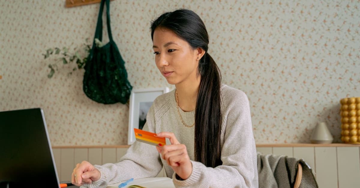 Woman reviewing finances online while holding a credit card for debt consolidation loans